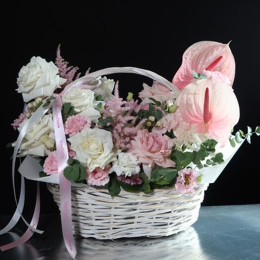 Flowers basket, delicate composition with twisted roses, a basket with anthurium and eastoma