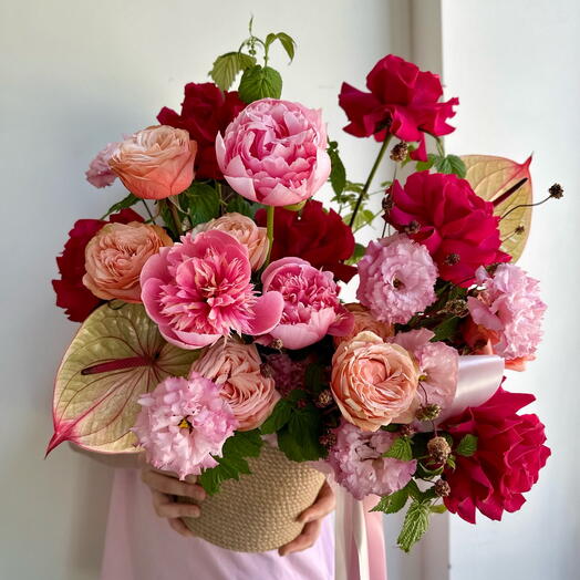 Bright summer composition in handmade wicker. Peonies, anthuriums, French roses