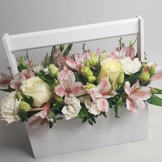 A composition with flowers in a box with white roses and alstromerias