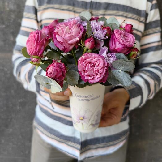 A glass with a rose of a bush with eucalyptus