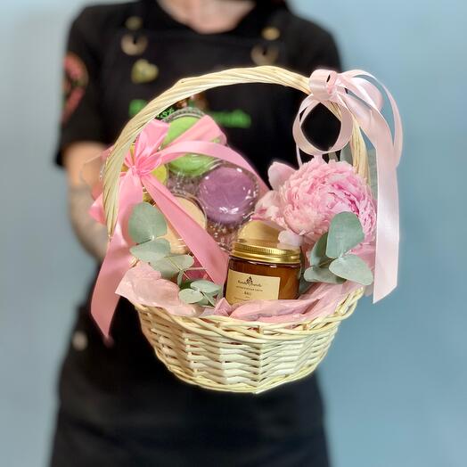 Подарочный набор с ароматической свечой, пирожными макарон и пионом в плетеной корзине