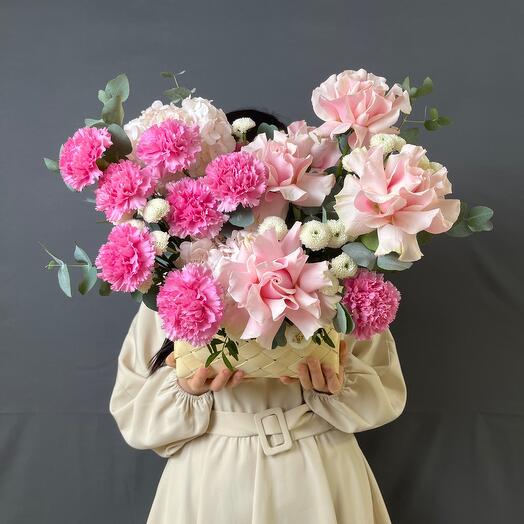 Flower composition in a basket in a delicate range with French roses, diatus, hydrangea and a bush chrysanthemum