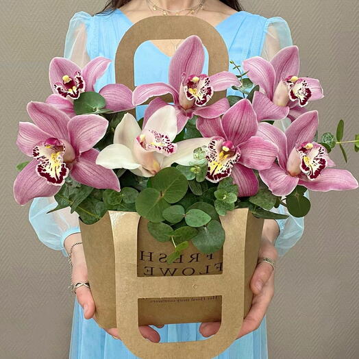 A handbag with pink orchids and a white orchid. Flowers and eucalyptus basket