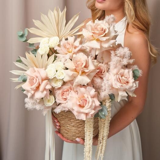 Basket with flowers. French roses in woven pots with dried flower twigs and aromatic eucalyptus